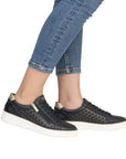 Model wearing black Remonte D2E03 lace-up sneakers with jeans, showcasing stylish cut-out design and comfort fit.