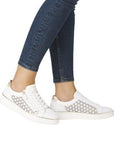 Model wearing white Remonte D2E03 lace-up sneakers with jeans, highlighting stylish laser-cut leather and gold heel detail.