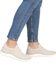 Beige slip-on sneakers worn with blue jeans.