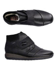 Pair of Black Leather Velcro Ankle Boot with accent stitching, white wool lining, brown midsole and black treaded outsole.