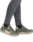 Green sneakers with gold accents worn with gray jeans.