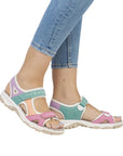 Model wearing multicolor Women's Rieker 68866 Backstrap Sandal with jeans, highlighting its vibrant design and walking support.