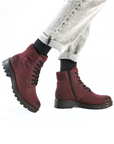 Red combat boots with black soles worn with light grey jeans.
