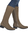 Woman wearing tall taupe boots and blue jeans.