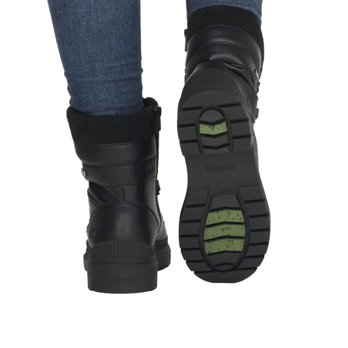 Legs in jeans wearing black leather combat boot with green ice grip inserts in rubber outsole.
