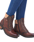 Legs in jeans wearing brown leather lace up ankle boot with stacked heel.
