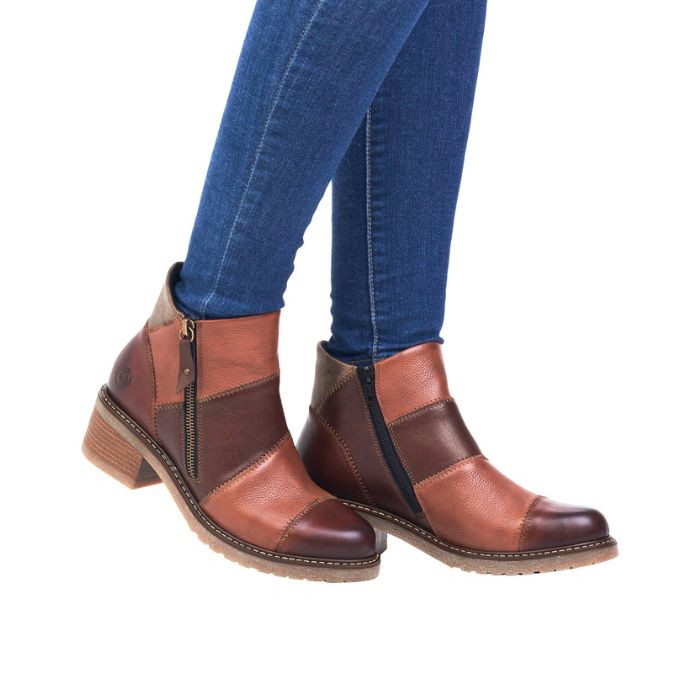 Legs in jeans wearing light and dark brown patched ankle boot with stacked heel and outside zipper.