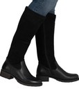 Woman wearing black tall boots with low block heel and blue jeans.