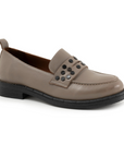 Beige loafer shoe with black circle embellishments on strap and black think outsole.