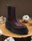 Women's Casta Nemesis Chelsea Boots displayed on wood with cotton decor, showcasing premium handmade leather and fall fashion appeal.