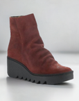 Side view of red suede Women's FLY London Baan Wedge Bootie featuring cushioned footbed and chunky black sole for stylish support.