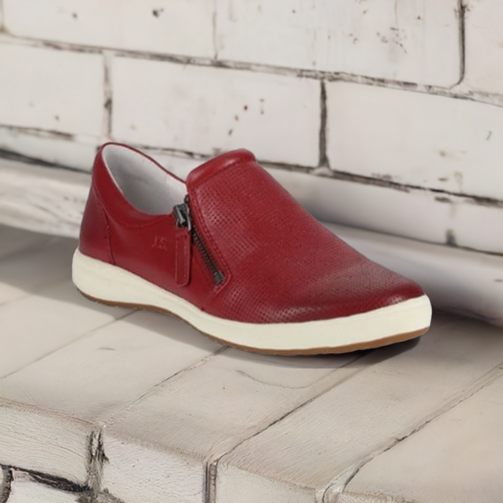 Red Josef Seibel Caren 22 leather slip-on sneaker for women displayed on a rustic white bench, combining comfort and casual elegance.