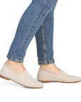 Beige woven flats worn with blue jeans.