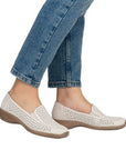 Women in blue jeans wearing beige perforated loafers.