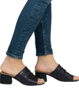 Model wearing Women's Rieker 64687 Slide Heel with jeans, highlighting the sandal's versatile black leather and mid-height heel.