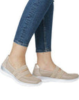 Model wearing Women's Rieker L3281 Mary-Jane Flat in beige, styled with jeans, showcasing its sporty comfort and slip-on casual design.