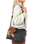 Person wearing a white sweater with a black handbag featuring a fur pom-pom.