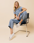 Women in Jean jumper sitting on chair with white rhinestone covered sneakers.