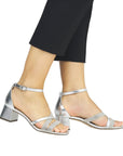Model wearing silver Remonte D1L51 sling-back heels with ankle strap and glitter accents, ideal for formal or evening wear.
