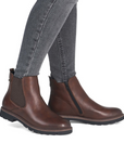Brown leather chelsea boots worn with gray jeans.