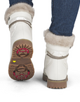 White winter boots with fur trim worn by a person with blue jeans.