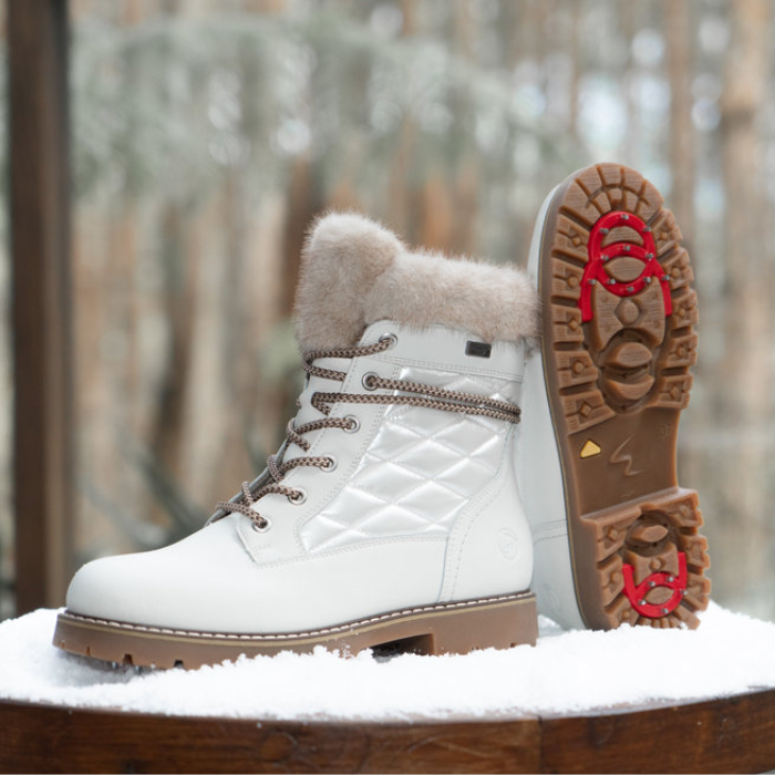 White winter boots with fur lining on a snowy surface.