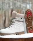 White winter boots with fur lining on a snowy surface.