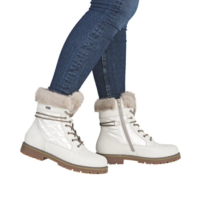 White winter boots with fur trim worn with blue jeans.