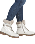 White winter boots with fur trim worn with blue jeans.