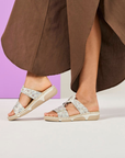 Person wearing floral slide sandals with a brown skirt.