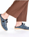 Model wearing the Rieker N4210 women's clog with brown pants, highlighting the casual slip-on style and cushioned comfort for daily wear.