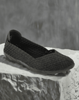 Black Bernie Mev Catwalk Ballet Flat displayed on stone surface, highlighting its woven vegan upper and sleek silhouette.