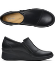Top and Profile of Black leather wedge ankle slip-on shoe. Has a detailed silver button above side zipper. Small detailed diagonal stitching on toe. Padded tan footbed has the black Clarks logo at heel.