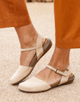 Beige sandals with brown outsoles worn by a person in orange pants.