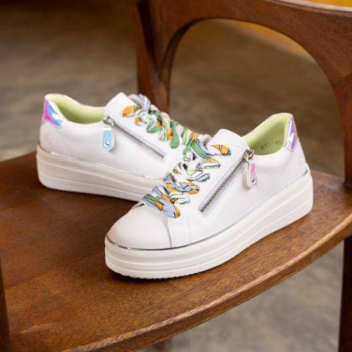 White Remonte D1C06 women's platform sneakers with colorful laces and zipper, displayed on a wooden chair for lifestyle appeal.
