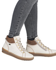 White high-top sneaker boots with brown accents worn with gray jeans.