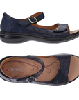 Pair of Navy blue floral perforated design on side of sandals with a gold buckle accent on Velcro strap, closed side and back, tan Revere logo'd footbed and black outsole.