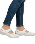 Women in blue jeans wearing white perforated Rieker Mary-Janes.