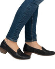 Model wearing Women's Rieker 43754 heeled shoes with jeans, showcasing stylish, flexible leather pumps ideal for casual or office outfits.