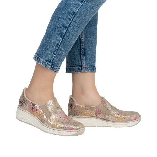 Model wearing Women's Rieker 48761 Slip-On Shoe with jeans, showcasing casual style and comfort with floral wedge design.