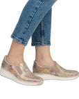 Model wearing Women's Rieker 48761 Slip-On Shoe with jeans, showcasing casual style and comfort with floral wedge design.