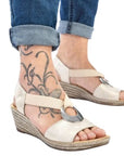 Model wearing beige Rieker 624H6 Sling-Back Wedge Sandals with tattooed ankle. Elegant and supportive for casual outfits.