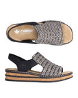 Pair of Backstrap Sandals with a black and white woven upper, side elastics, tan Rieker logo'd footbed, and faux cork midsole with black layers.