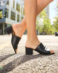 Outdoor lifestyle shot of Women's Rieker 64687 Slide Heel worn on city street, emphasizing comfort and elegance in everyday fashion.