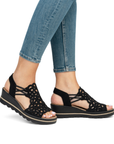 Black sparkly wedge sandals worn with blue jeans.