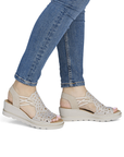 Beige sparkly wedge sandals worn with blue jeans