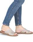 Beige sparkly slide sandal worn with blue jeans.