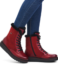 Red winter boots with fur trim worn with blue jeans.
