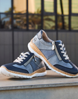 Pair of blue sneakers on a wooden surface with a blurred outdoor background.