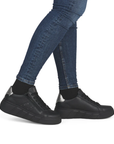 Black sneakers worn with blue jeans.